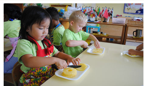 Two children cutting pineapple